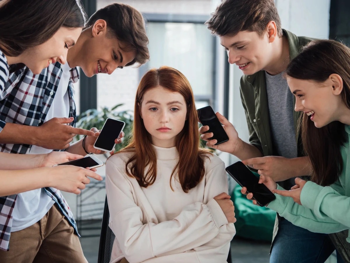 A imagem mostra uma rapariga a ser alvo dos comentários de um grupo de jovens. Neste caso, a sua expressão triste mostra que as palavras utilizadas pelo grupo nas redessociais, representadas pelos telemóveis, serão ofensivas. O poder das palavras aqui é representado pela tristeza da rapariga. Poderá ser um exemplo de cyberbullying.
